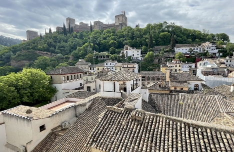 Fantastisk och annorlunda vy av palatset Alhambra i Granada, med de gamla hustaken i kvarteret El Albaicín i förgrunden.